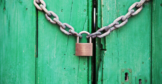 A rustic green wooden door secured with a heavy chain and padlock, symbolizing security.