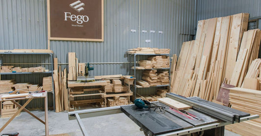 Interior of a wood workshop featuring a table saw, lumber stacks, and carpentry tools in an organized industrial setting.