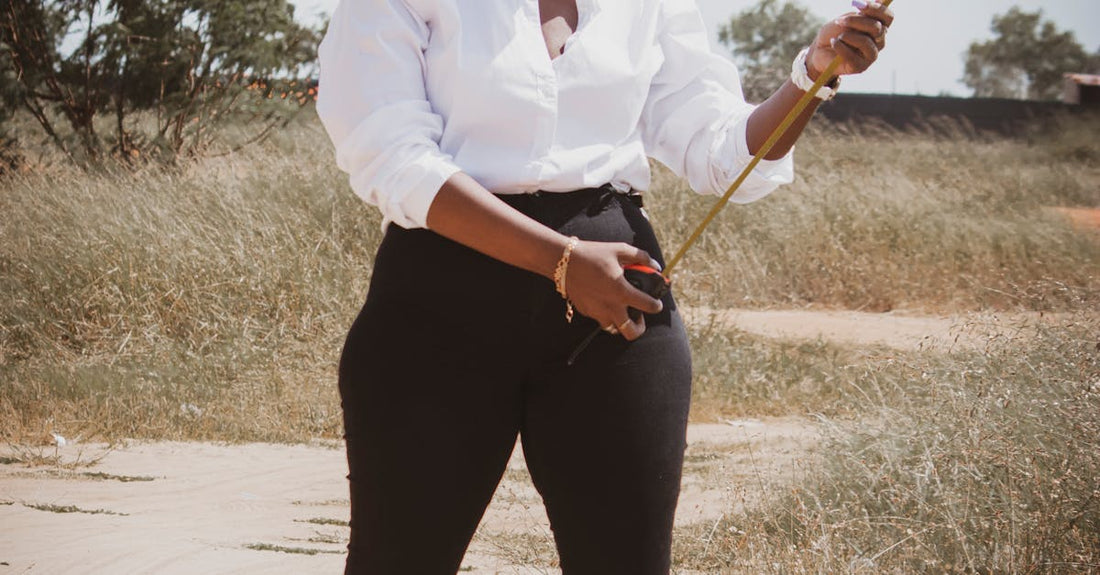African female civil engineer wearing hard hat measuring outdoors with a tape. Ideal for industry or construction themes.