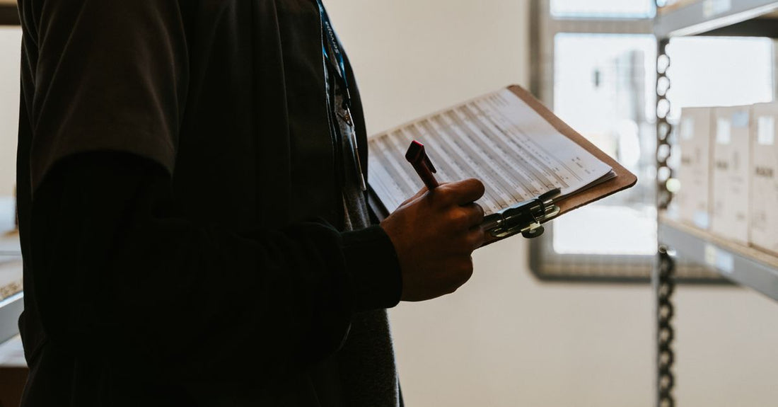 Industrial worker managing inventory in a warehouse with a clipboard and checklist.