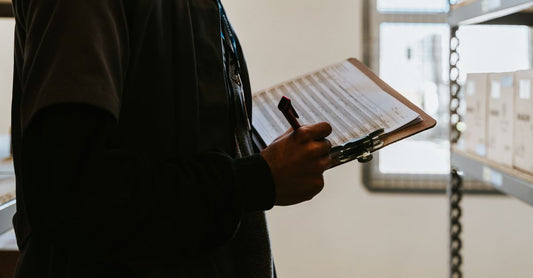 Industrial worker managing inventory in a warehouse with a clipboard and checklist.