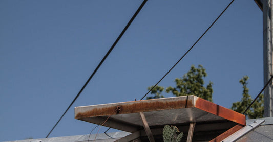 A close-up view of a roof vent against a clear blue sky, featuring angular lines and metal textures.