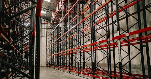 Spacious warehouse interior featuring empty metal racks and high ceiling.