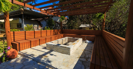 Inviting patio with a stone fire pit and wooden benches under a pergola, perfect for outdoor relaxation.