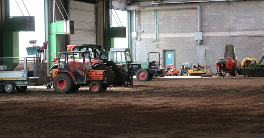 Image of various tractors and farm machinery stored in a large indoor facility.