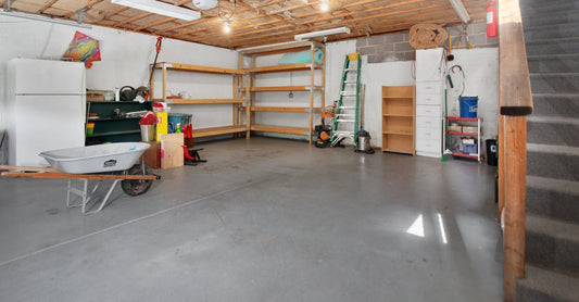 Spacious garage interior with storage shelves, tools, and a wheelbarrow, ideal for home organization.