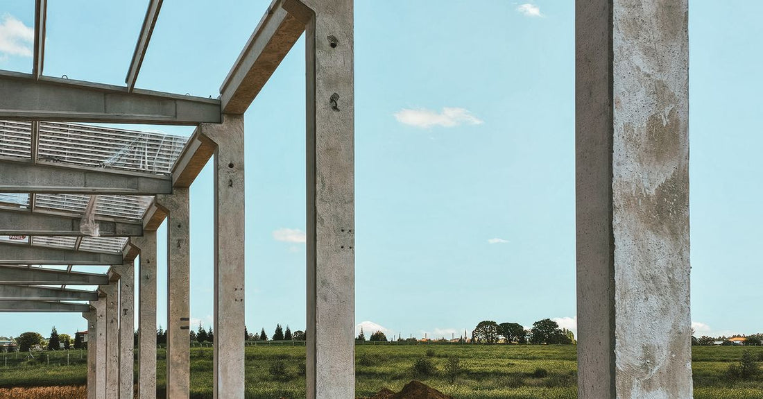 Concrete pillars in a rural setting form part of a new building structure under construction.