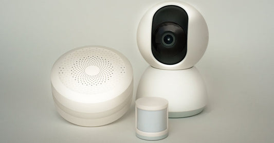 Modern smart home devices including a camera and sensors on a neutral background.