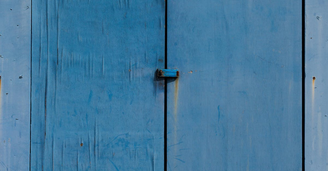 Rustic blue wooden garage door with metal hinges on barn exterior.