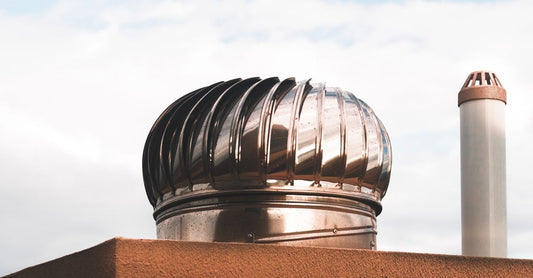 Close-up of a metal rotating roof vent on a sunny day with blue sky in the background.