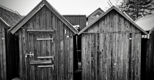 Two rustic wooden sheds captured in a black and white photograph, creating a vintage feel.