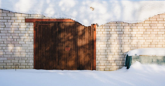 A snow-covered brick garage door under a blue sky with winter shadows.