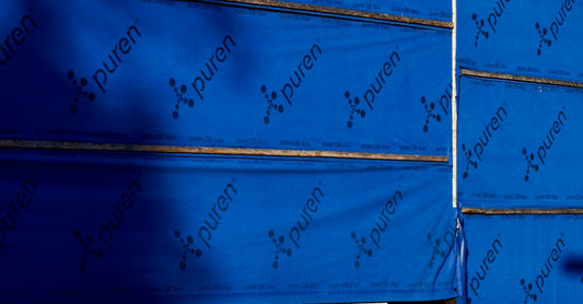 Building under construction with blue insulating wrap showing brand name puren