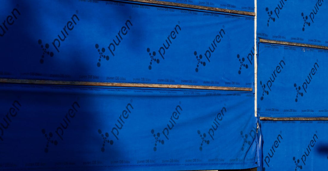 Building under construction with blue insulating wrap showing brand name puren