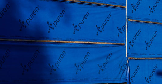 Building under construction with blue insulating wrap showing brand name puren