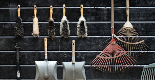 Neatly arranged garden tools hanging on a rustic wooden wall.