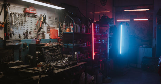 Dimly lit garage featuring neon lights and automotive tools creating a moody ambiance.