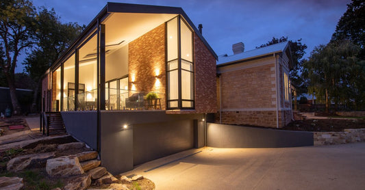 Contemporary residential cottage exterior with shiny lamps near walkway under sky in twilight