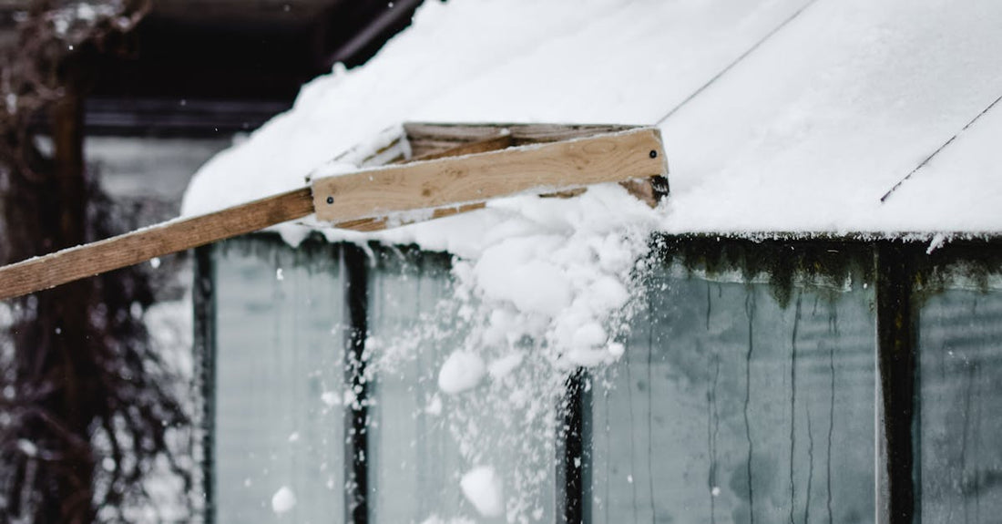 Snow being removed from a shed roof in snowy Estonian winter landscape.
