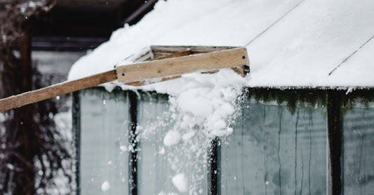 Snow being removed from a shed roof in snowy Estonian winter landscape.