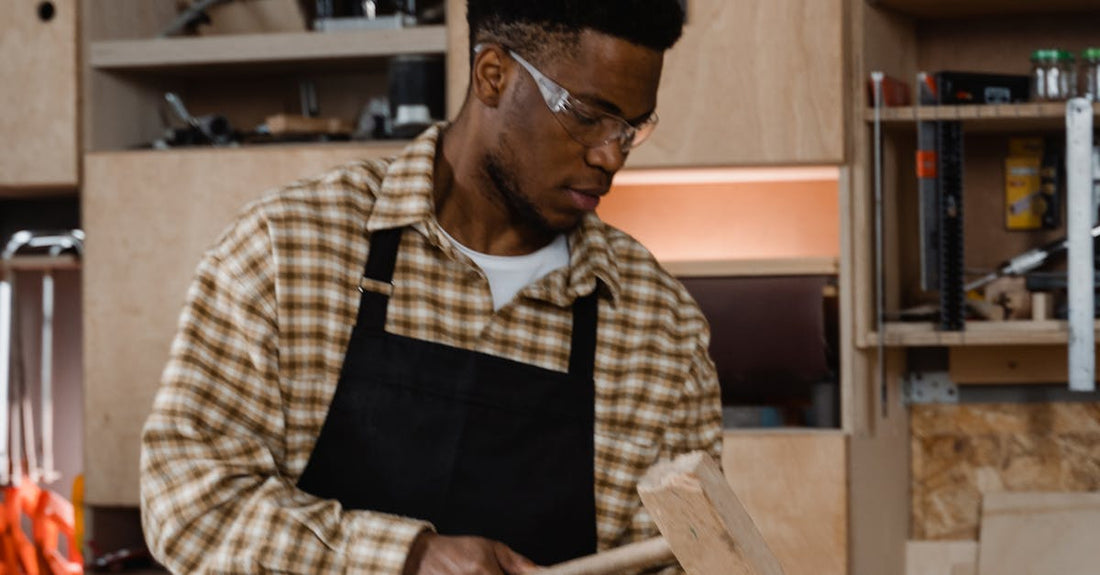 Carpenter working with tools in a well-equipped workshop, focused on woodworking.