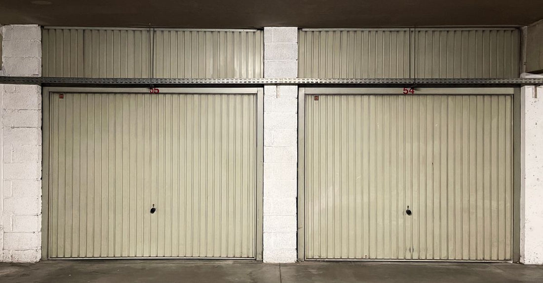 Two closed garage doors inside an empty warehouse space.
