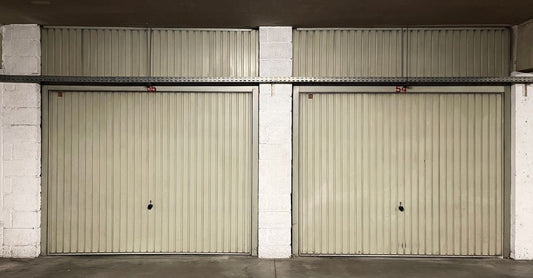 Two closed garage doors inside an empty warehouse space.