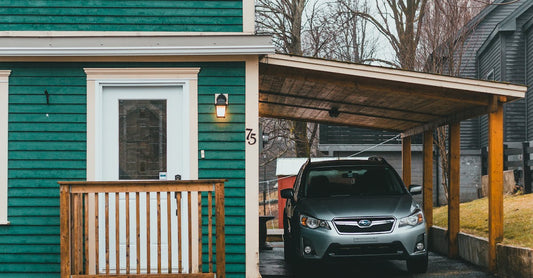Exterior of green building with automobile parked under canopy near wet asphalt road in autumn