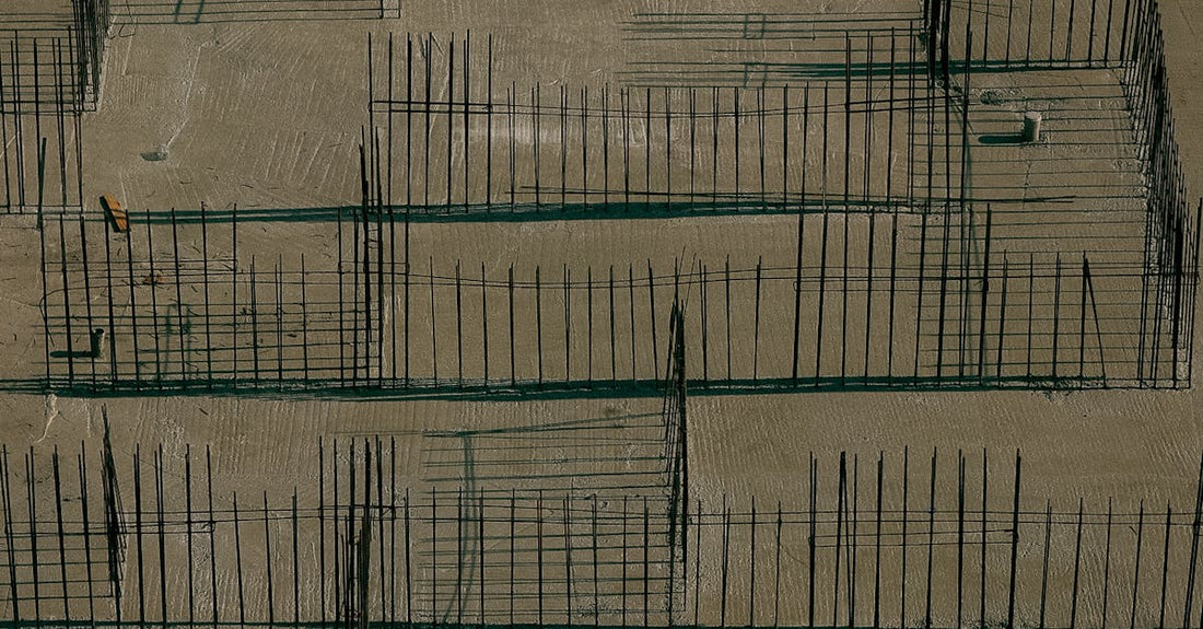 Drone aerial view of a construction site with concrete foundations and metal reinforcements.