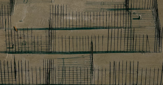 Drone aerial view of a construction site with concrete foundations and metal reinforcements.